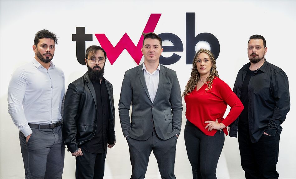Equipe da tWeb Marketing reunida em frente ao logo da agência Equipe da tWeb Marketing reunida em frente ao logo da agência
